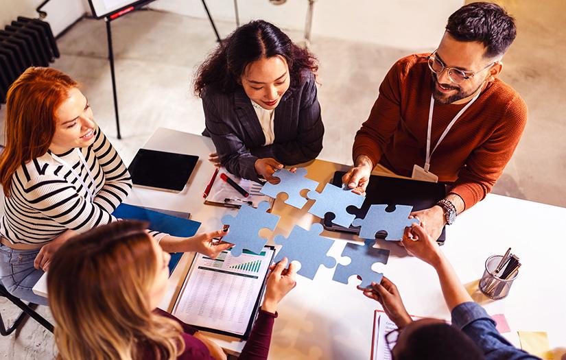 groupe de personnes assemblant des pièces de puzzle sur une table